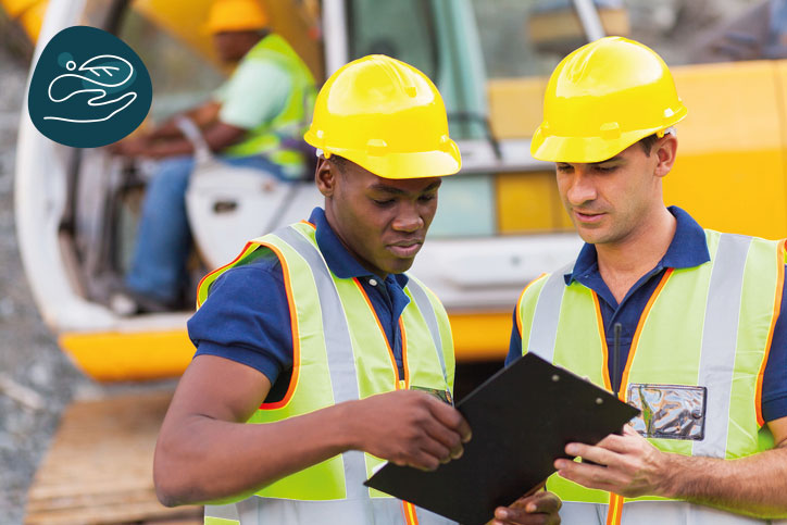 Two people wearing personal protective equipment working together on a construction field