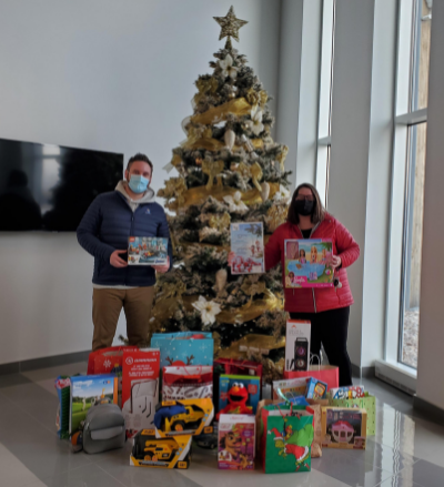 Two individuals standing in front of a Christmas tree holding presents.