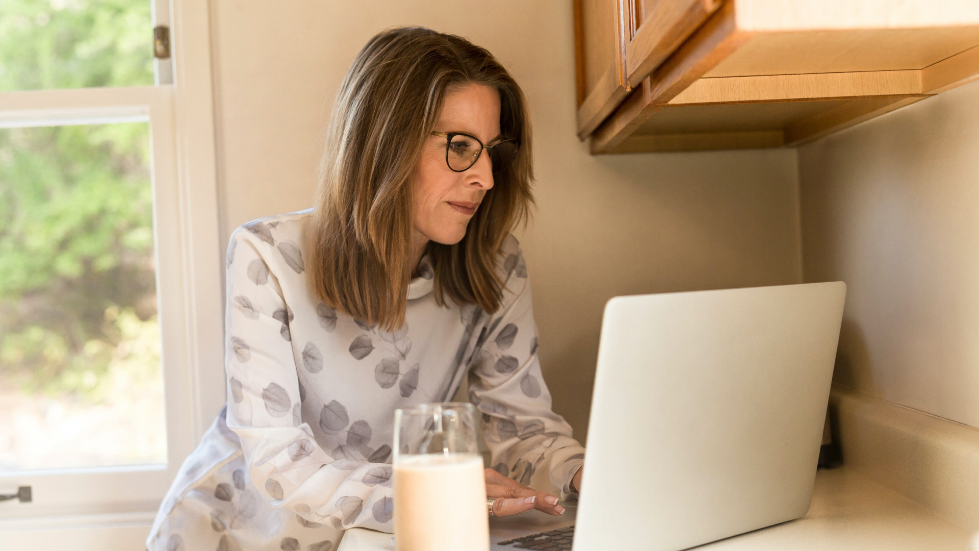 Une femme dans sa cuisine s'inscrit à un webinaire sur son ordinateur portable